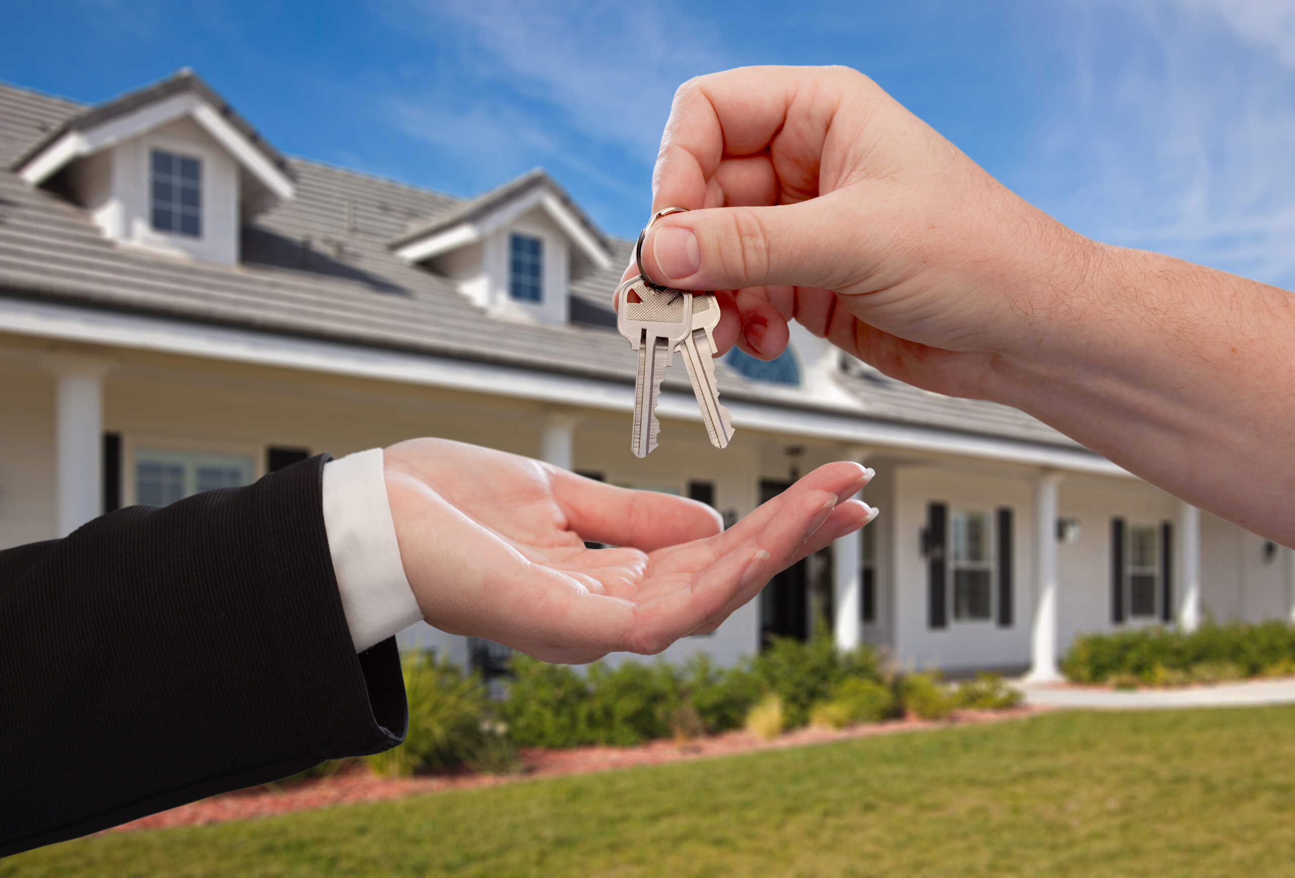 Handing Over the House Keys in Front of a Beautiful New Home.