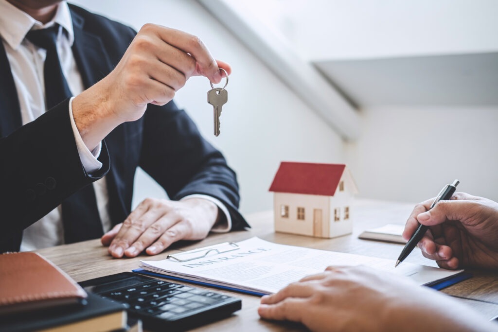 A real estate agent hands over a key to a client