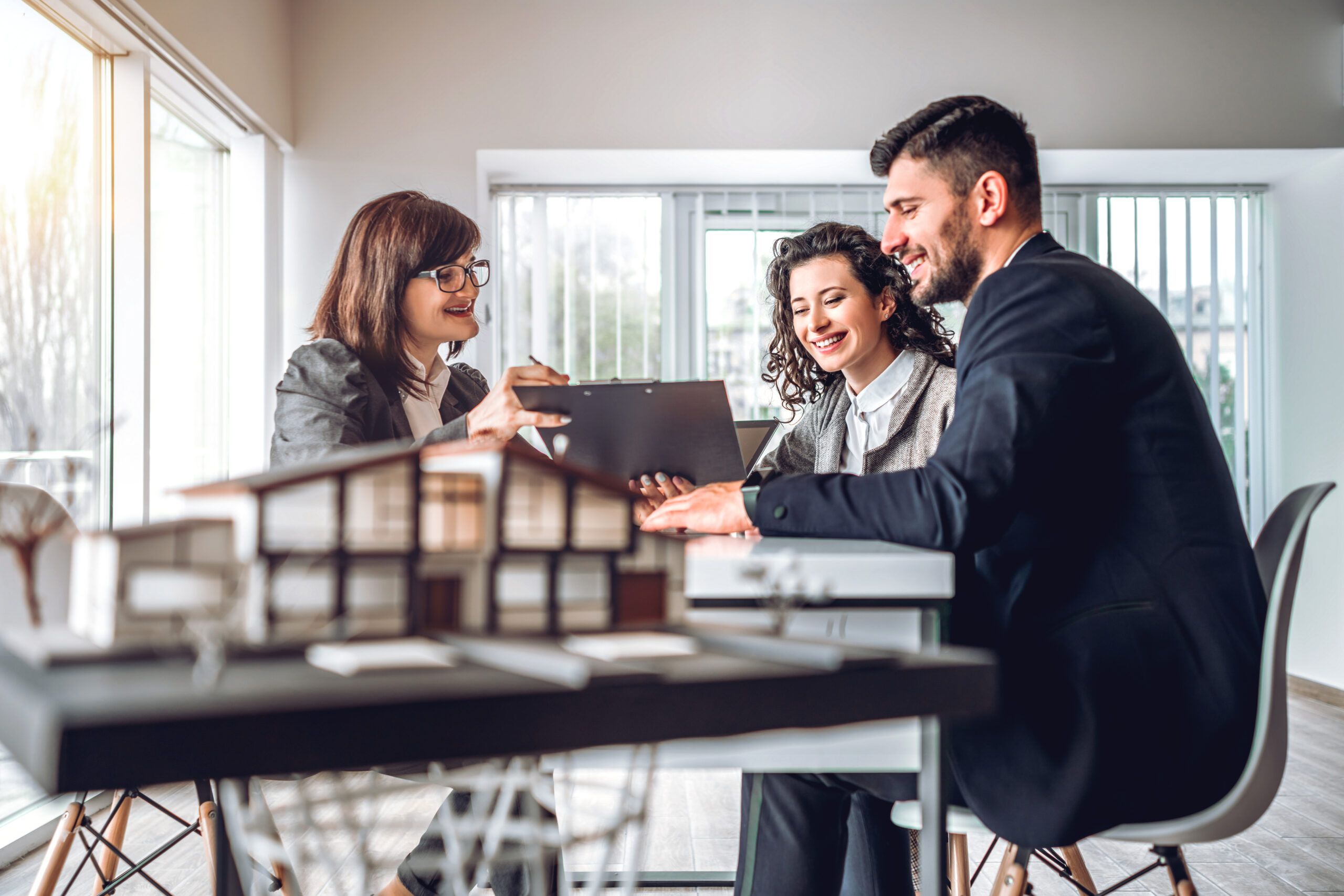 Three professionals engage in a collaborative discussion over a clipboard