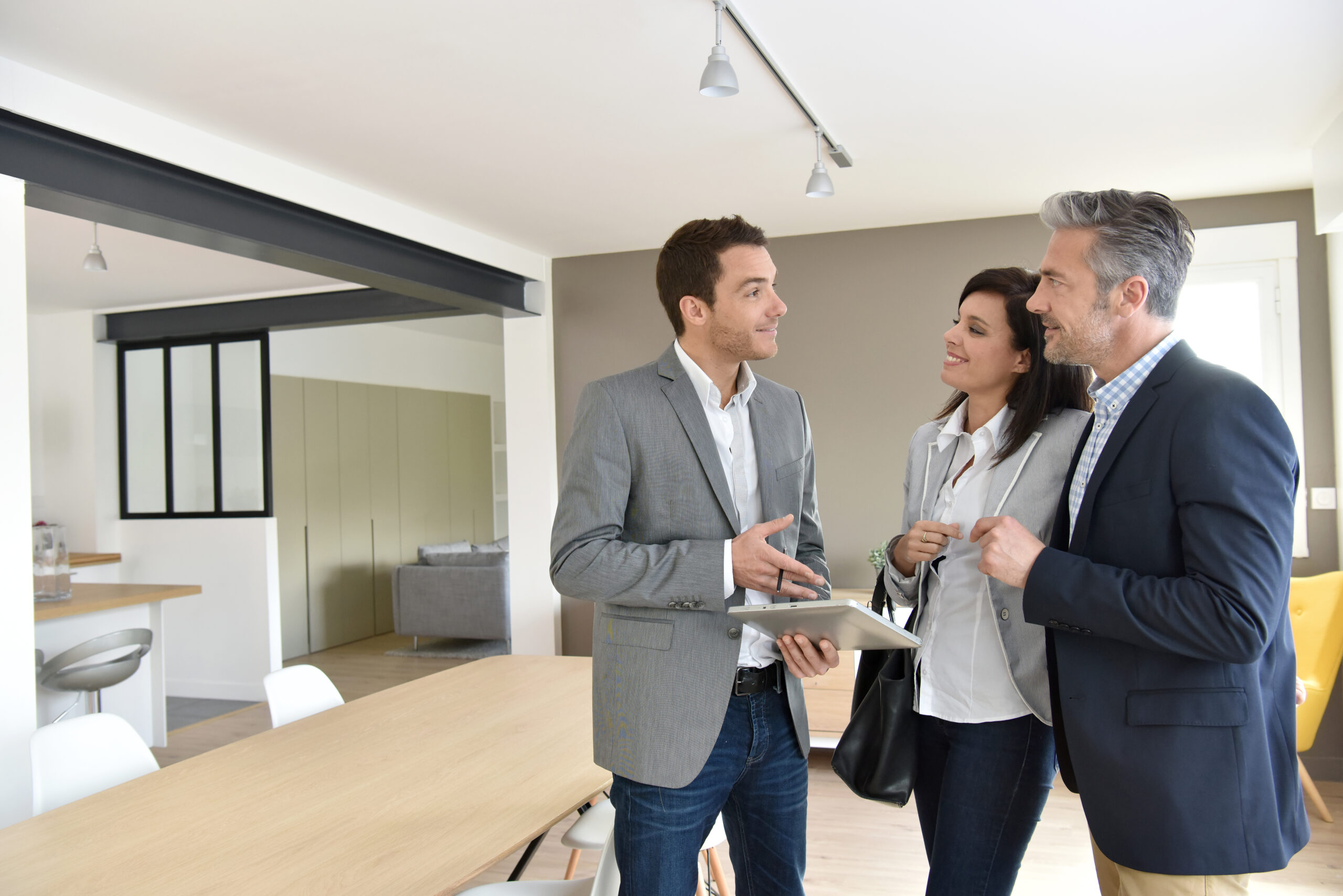 A real estate agent discusses property details with a couple in a modern living space
